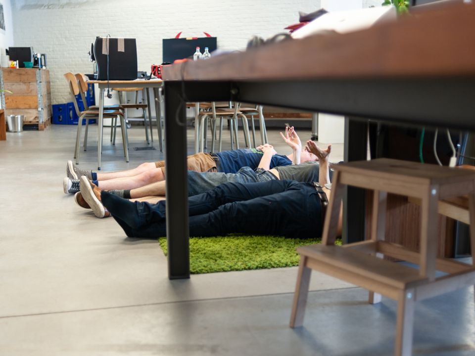 Een paar medewerkers van 3sign liggen op een groene mat in het kantoor.
